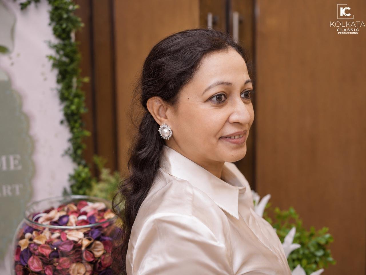 Smita Modi in a champagne silk shirt with a pearl earring, smiling in profile